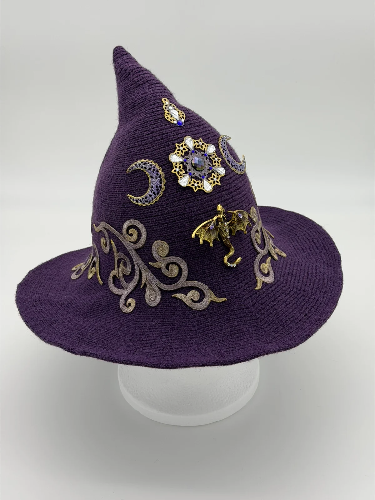Purple pointed hat embellished with moons, gold scrolls, jewels, and a tiny dragon