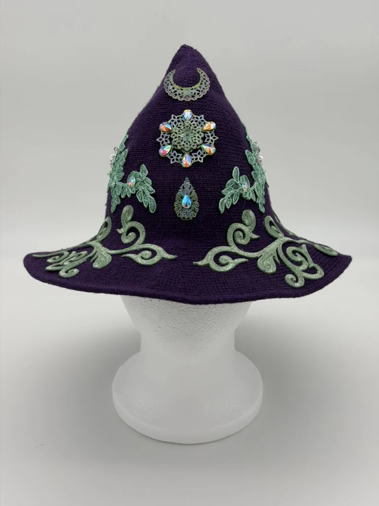 Plum witch hat decorated with green vines, a crescent moon, and sparkling jewels