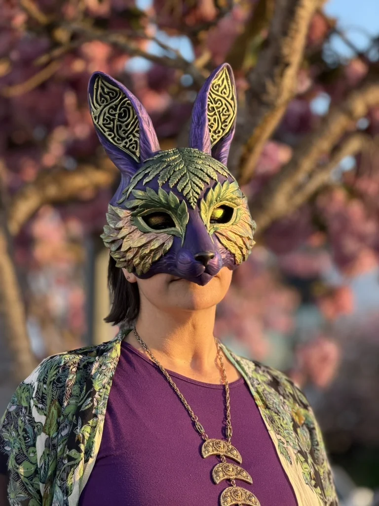 Purple rabbit mask with sculpted leaves and tall gold-patterned ears, worn outdoors